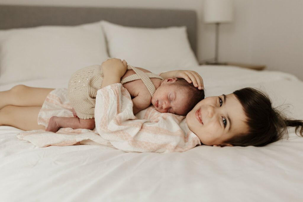 newborn photography capturing a new baby sleeping on her big sisters chest