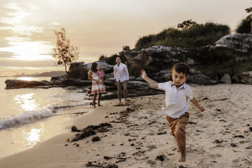 Family Photographer captures young boy running towards the camera infront of his family.